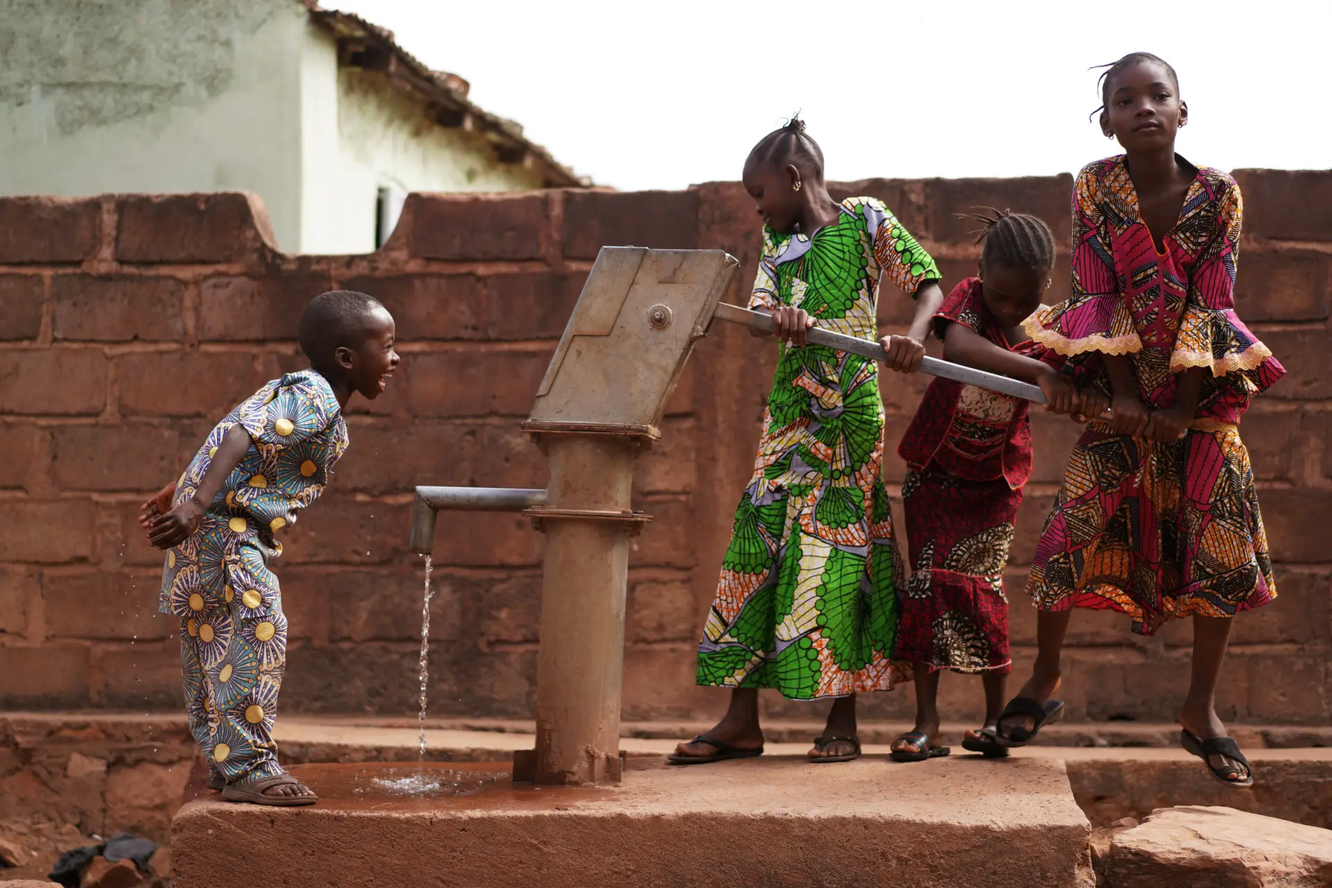 african children having fun at the water pump